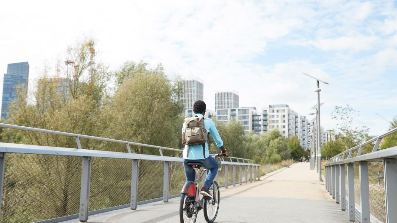 女孩骑着自行车在桥上向城市走去.